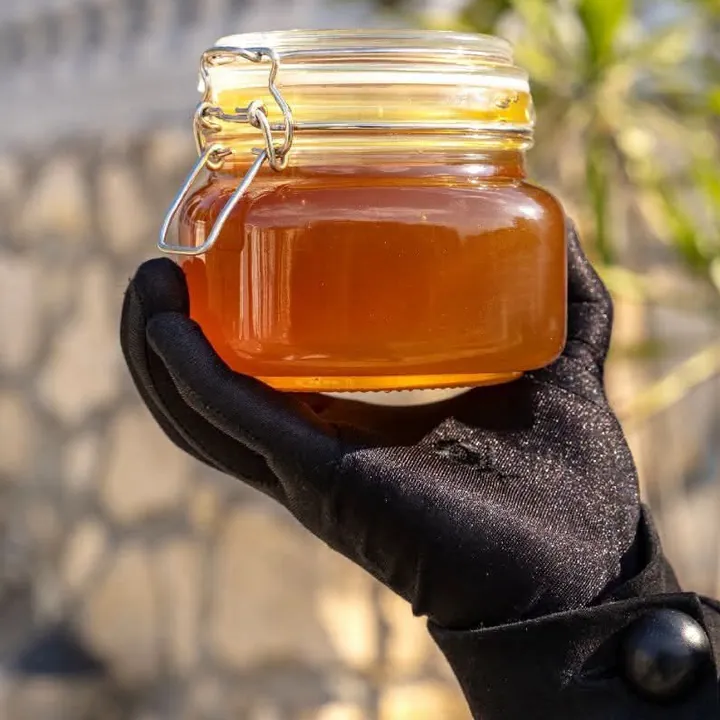 برطمان عسل من Maria's Honey في يد بقفاز أسود